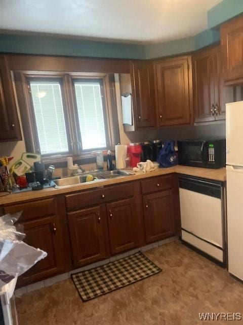 kitchen featuring white appliances, light countertops, and a sink