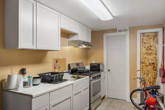 kitchen featuring light tile patterned floors, visible vents, white cabinets, under cabinet range hood, and stainless steel range with gas stovetop