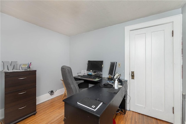 home office with light wood-style flooring and baseboards