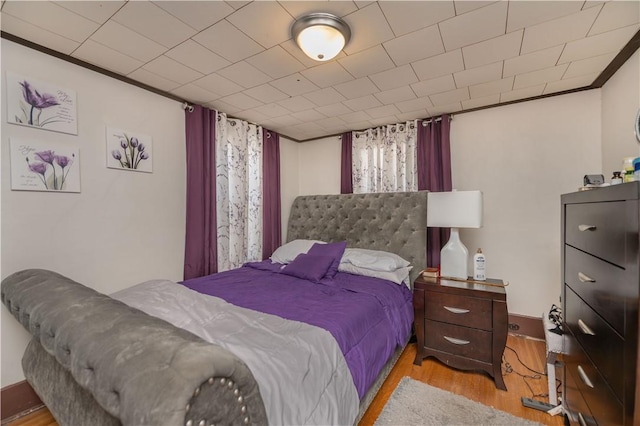 bedroom with ornamental molding and wood finished floors