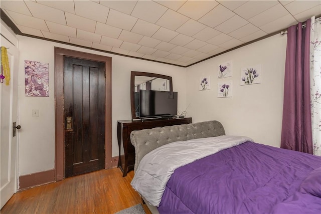 bedroom with baseboards, ornamental molding, and wood finished floors