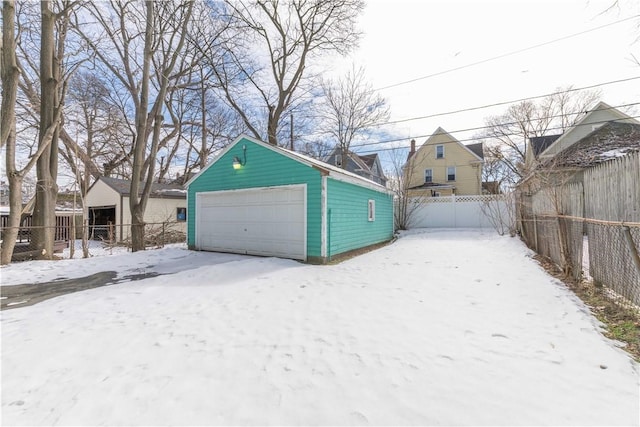 snow covered garage with a garage and fence