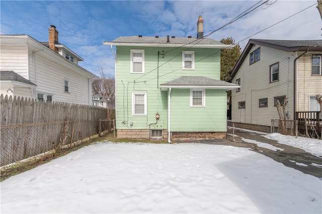 snow covered back of property featuring fence and a chimney