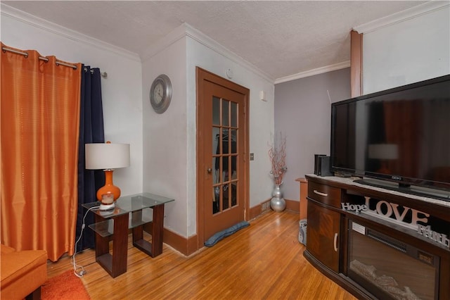 living area featuring light wood-style floors, crown molding, a textured ceiling, and baseboards