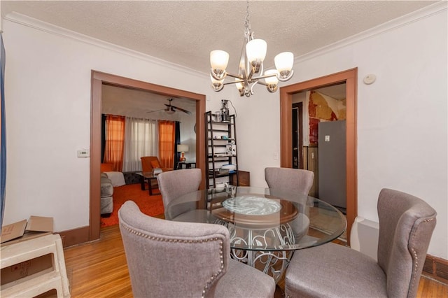 dining space with crown molding, a textured ceiling, an inviting chandelier, and wood finished floors