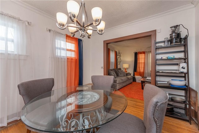 dining area featuring a notable chandelier, plenty of natural light, crown molding, and wood finished floors