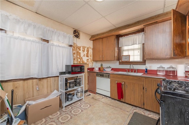 kitchen with a drop ceiling, white dishwasher, a sink, and brown cabinets