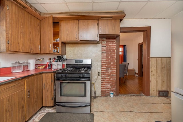 kitchen featuring a paneled ceiling, brown cabinetry, and gas stove