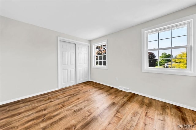 unfurnished bedroom with multiple windows, baseboards, and wood finished floors