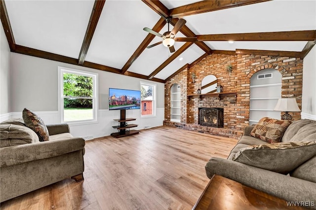 living room featuring built in shelves, vaulted ceiling with beams, a fireplace, wainscoting, and wood finished floors