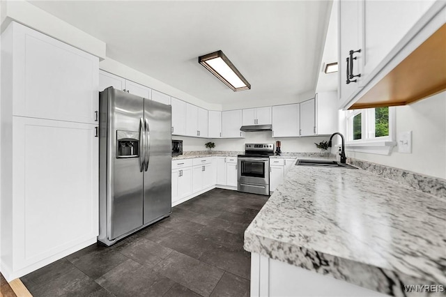 kitchen with appliances with stainless steel finishes, light stone countertops, under cabinet range hood, white cabinetry, and a sink