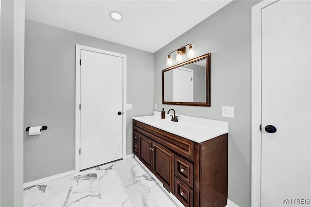 bathroom with marble finish floor, vanity, and baseboards