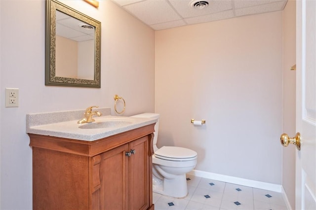 half bath with a paneled ceiling, visible vents, toilet, vanity, and baseboards