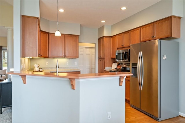 kitchen with a peninsula, a kitchen bar, and appliances with stainless steel finishes