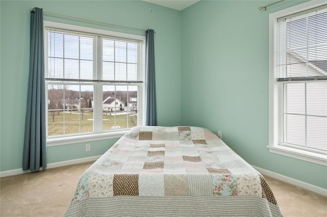 bedroom with baseboards, multiple windows, and light colored carpet