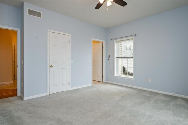 unfurnished bedroom featuring carpet flooring, ceiling fan, visible vents, and baseboards