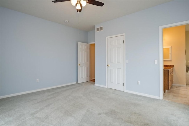 unfurnished bedroom featuring ceiling fan, connected bathroom, light colored carpet, visible vents, and baseboards