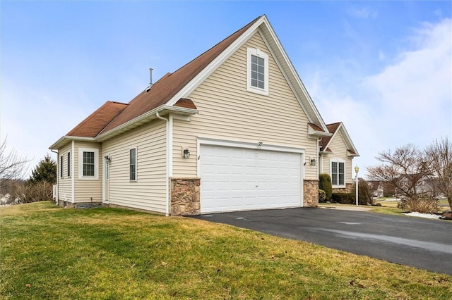 view of side of home featuring driveway, stone siding, an attached garage, and a yard