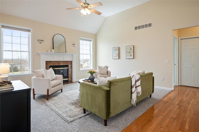 living room with a healthy amount of sunlight, visible vents, vaulted ceiling, and a fireplace