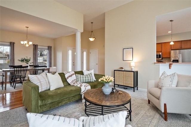 living area with ornate columns, baseboards, light wood finished floors, and a notable chandelier