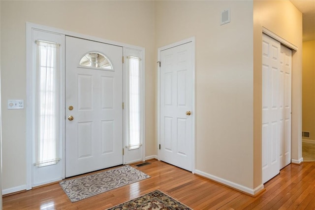 foyer entrance with light wood finished floors, visible vents, and baseboards