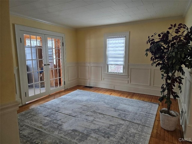 interior space featuring ornamental molding, french doors, wainscoting, and wood finished floors