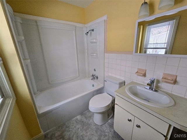 bathroom with toilet, a wainscoted wall, bathtub / shower combination, vanity, and tile walls