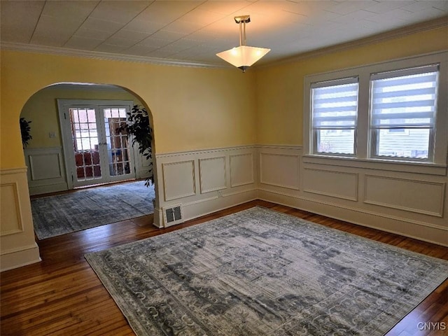 unfurnished dining area with arched walkways, dark wood-style flooring, visible vents, french doors, and crown molding