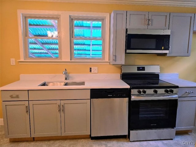 kitchen with appliances with stainless steel finishes, gray cabinets, light countertops, and a sink