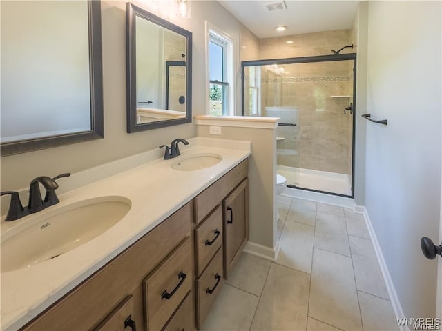 bathroom featuring double vanity, a sink, a shower stall, and tile patterned floors