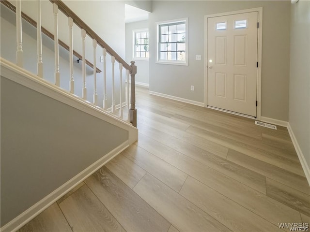 entryway featuring stairway, baseboards, visible vents, and wood finished floors