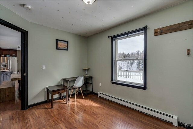 office space with baseboard heating, wood finished floors, and baseboards