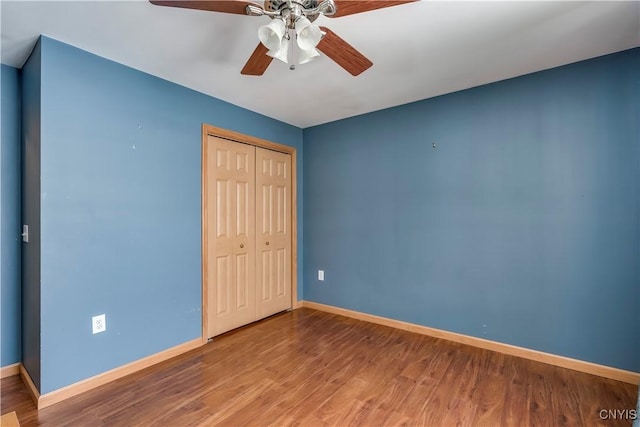 unfurnished bedroom with a closet, ceiling fan, baseboards, and wood finished floors