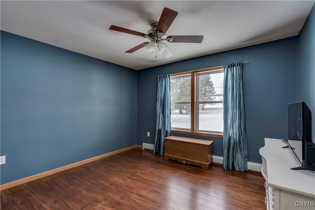 interior space featuring ceiling fan, a baseboard heating unit, dark wood-style flooring, and baseboards