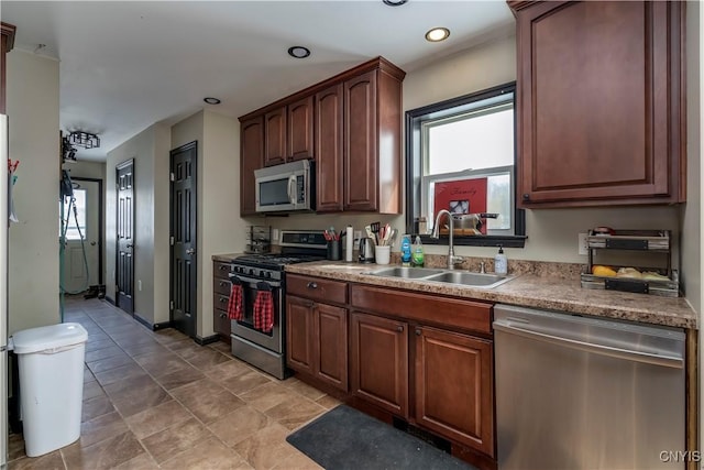 kitchen featuring baseboards, appliances with stainless steel finishes, a sink, and recessed lighting