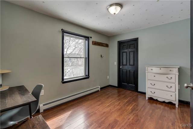 home office featuring baseboards, a baseboard heating unit, and wood finished floors