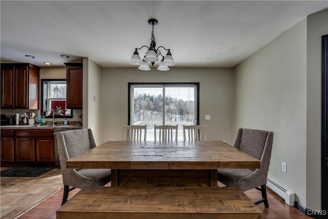 dining area with a chandelier, a baseboard radiator, baseboards, and wood finished floors