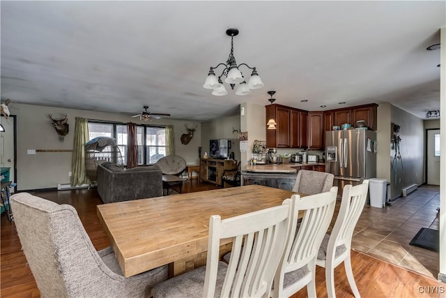 dining space featuring a baseboard radiator, light wood finished floors, and ceiling fan with notable chandelier