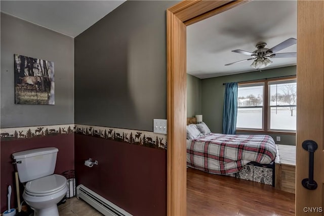 bedroom with a baseboard radiator, a ceiling fan, and wood finished floors