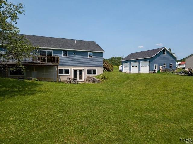 rear view of property featuring a garage, a yard, an outdoor structure, and a wooden deck