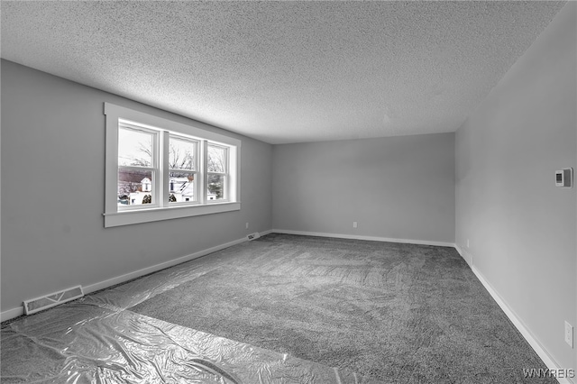 spare room with carpet flooring, visible vents, a textured ceiling, and baseboards