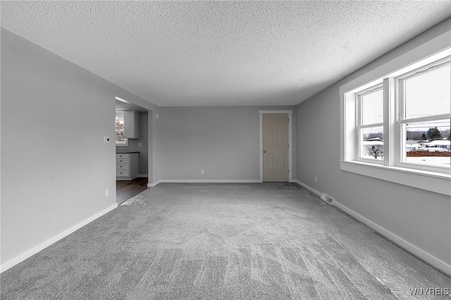 unfurnished living room with visible vents, carpet flooring, a textured ceiling, and baseboards