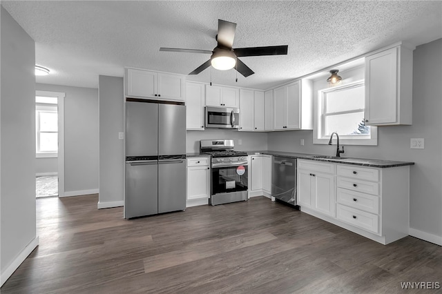 kitchen featuring dark countertops, white cabinetry, stainless steel appliances, and a sink