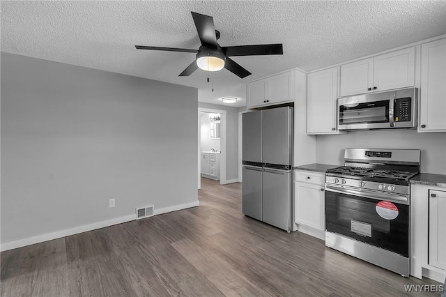 kitchen with visible vents, appliances with stainless steel finishes, a ceiling fan, white cabinetry, and wood finished floors