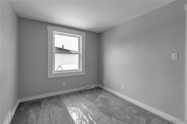 empty room with carpet, visible vents, and baseboards