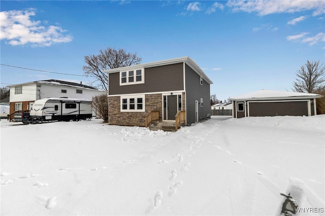 view of front of home featuring a garage, stone siding, and an outdoor structure