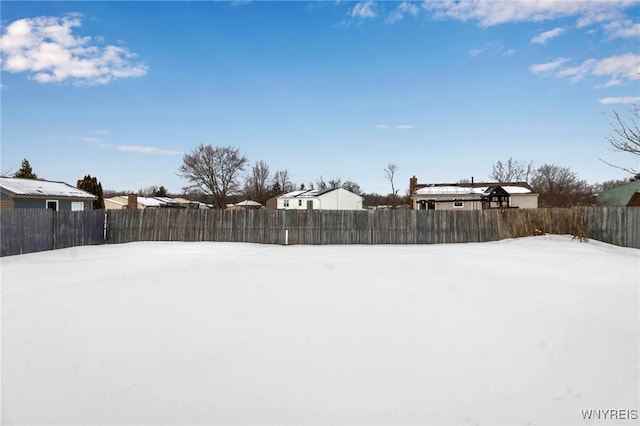 yard layered in snow featuring a fenced backyard