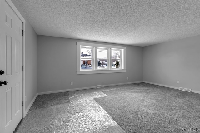 spare room with visible vents, a textured ceiling, and baseboards