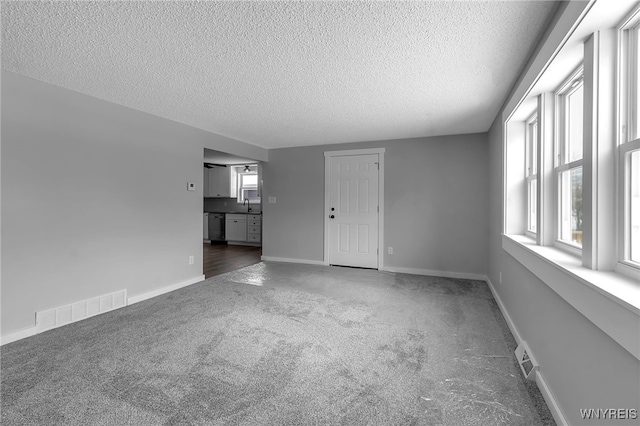 unfurnished living room featuring carpet floors, a wealth of natural light, a sink, and visible vents