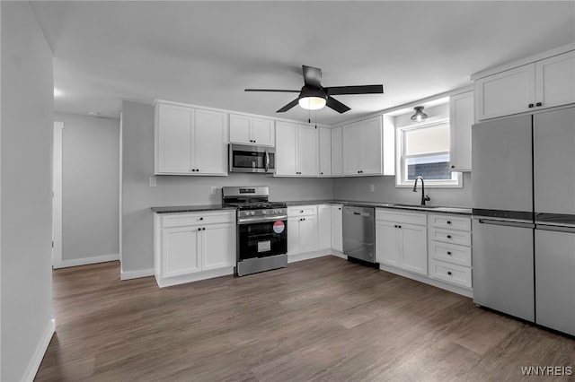 kitchen featuring dark countertops, white cabinets, stainless steel appliances, and a sink